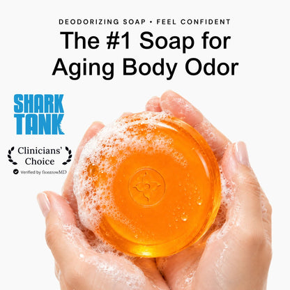 Unscented - A pair of hands holding a round, translucent orange body soap bar covered in white foam, with promotional text above reading 'The #1 Soap for Aging Body Odor' and the Shark Tank logo.